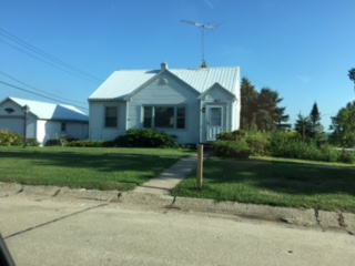 a small white house with a sidewalk in front of it